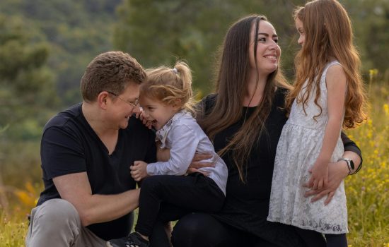 A joyful family enjoying a moment outdoors with their daughters.